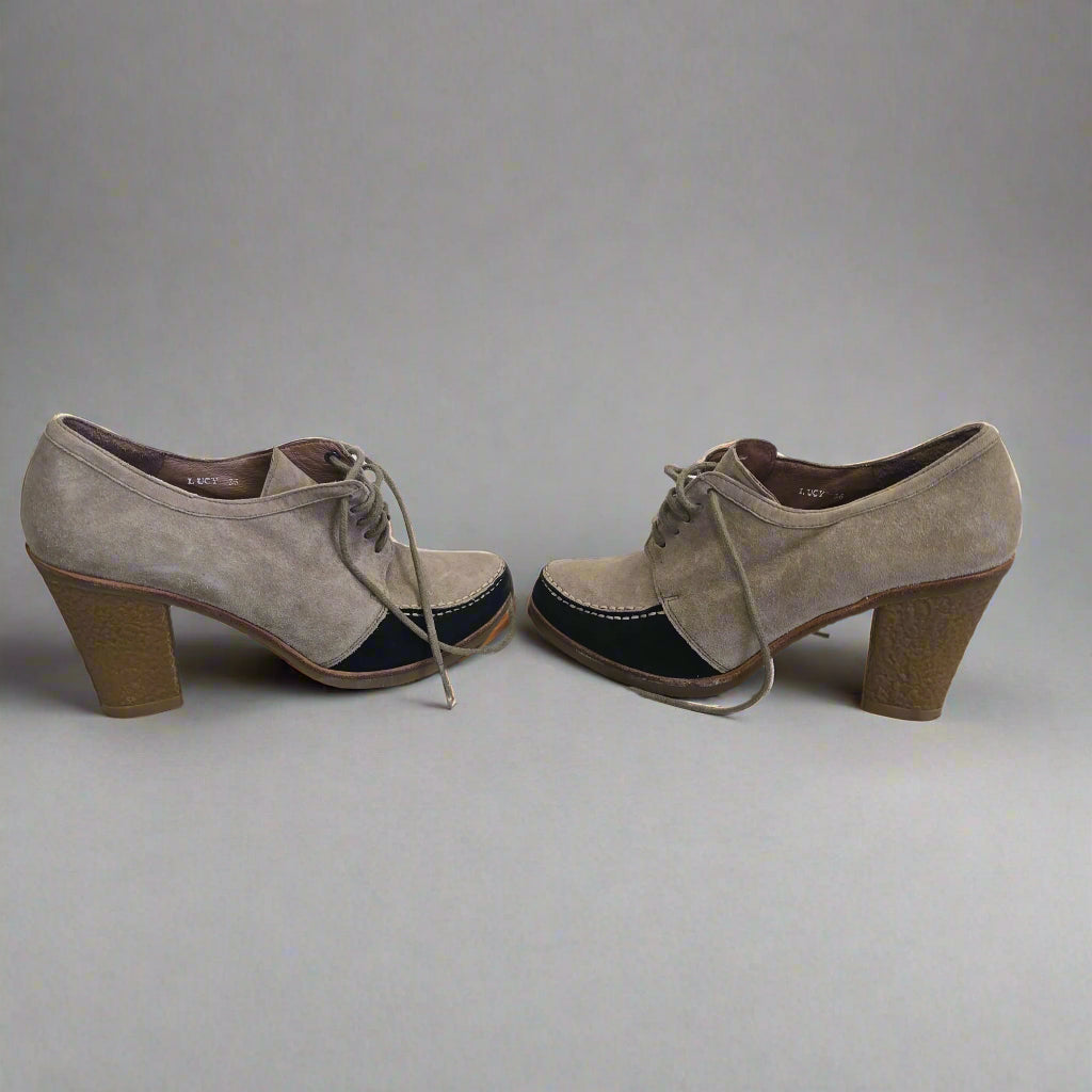 Pair of brown suede shoes hanging on a white wall.