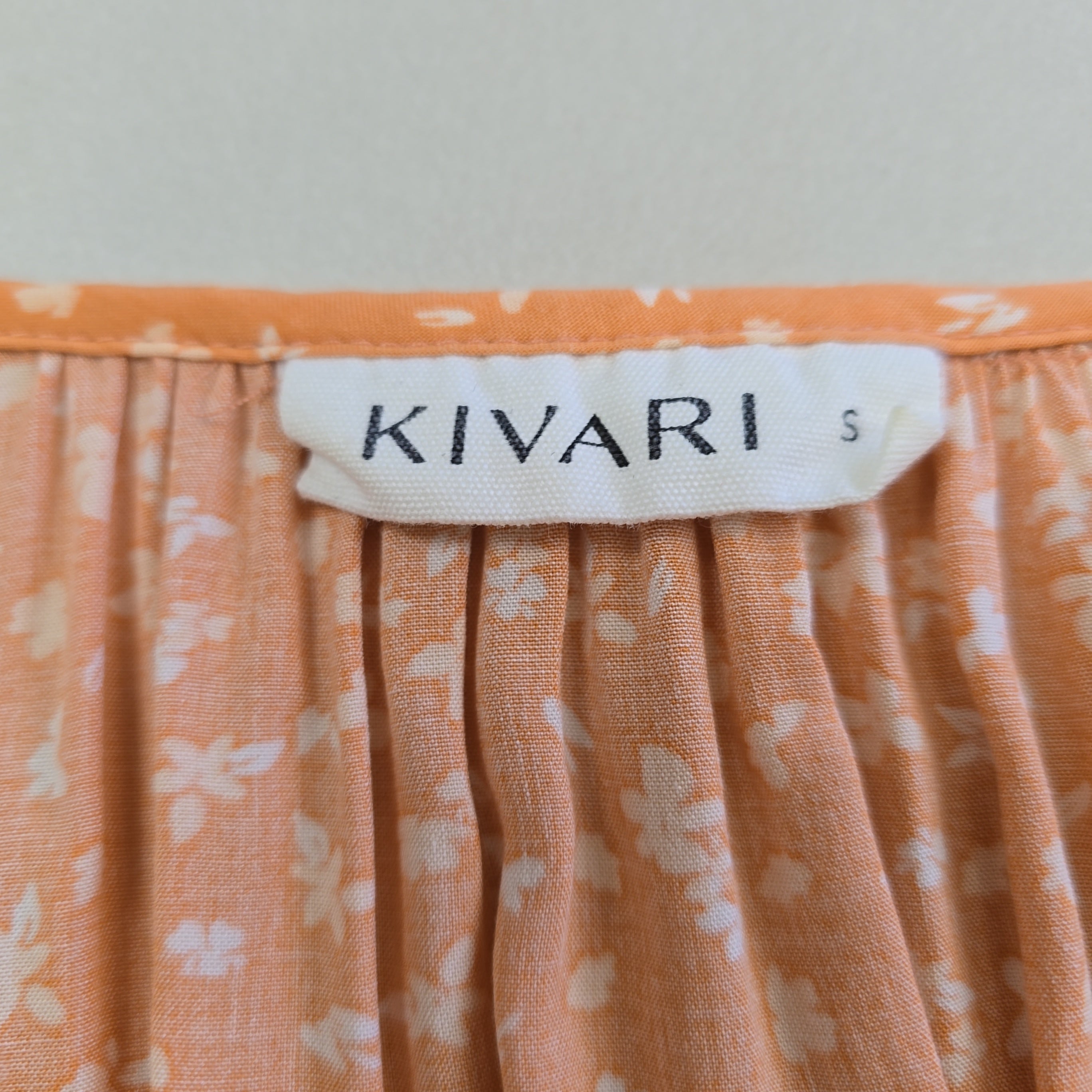 Close-up of an orange floral fabric with a 'KIVARI' label.