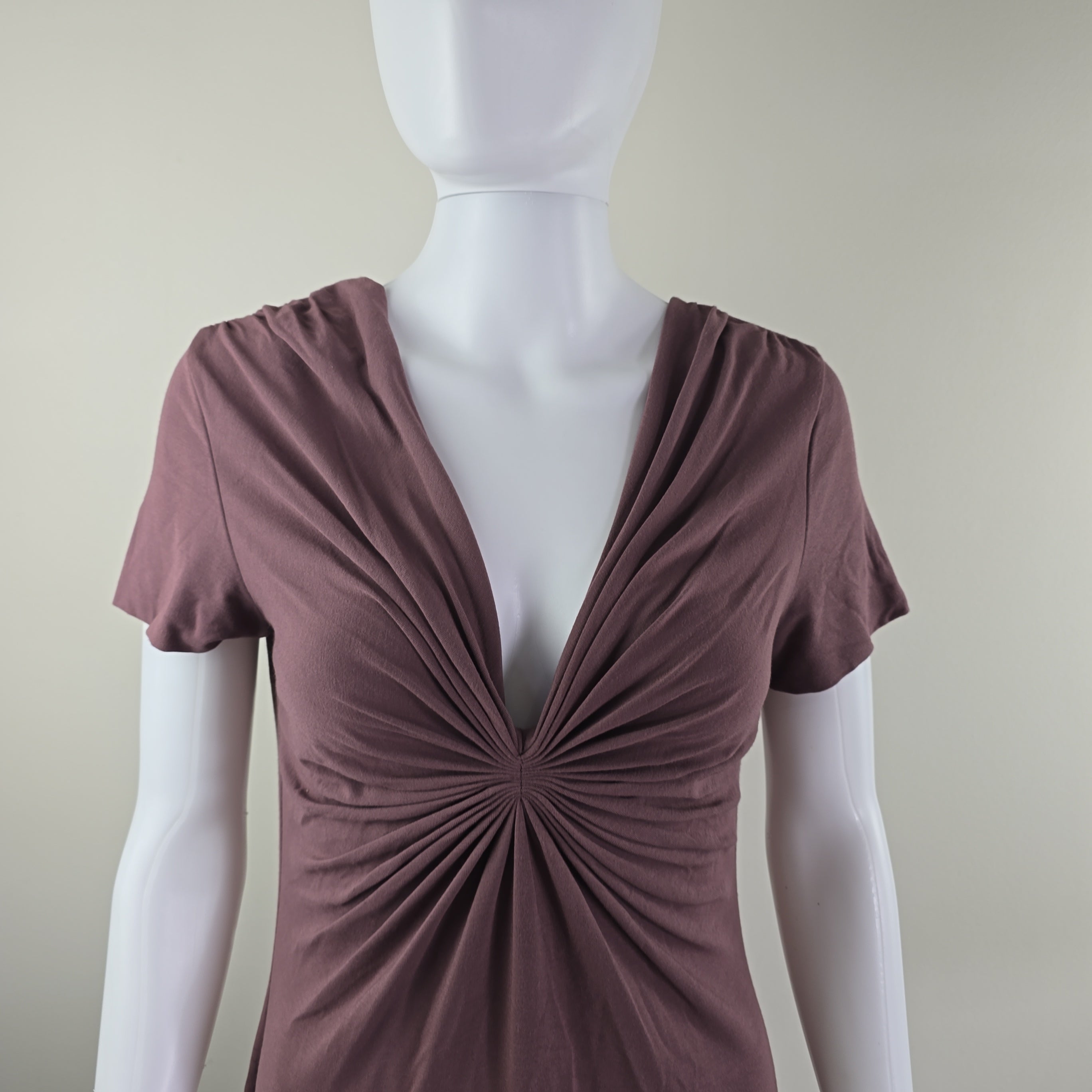 Brown dress with a starburst pattern on a mannequin against a beige background