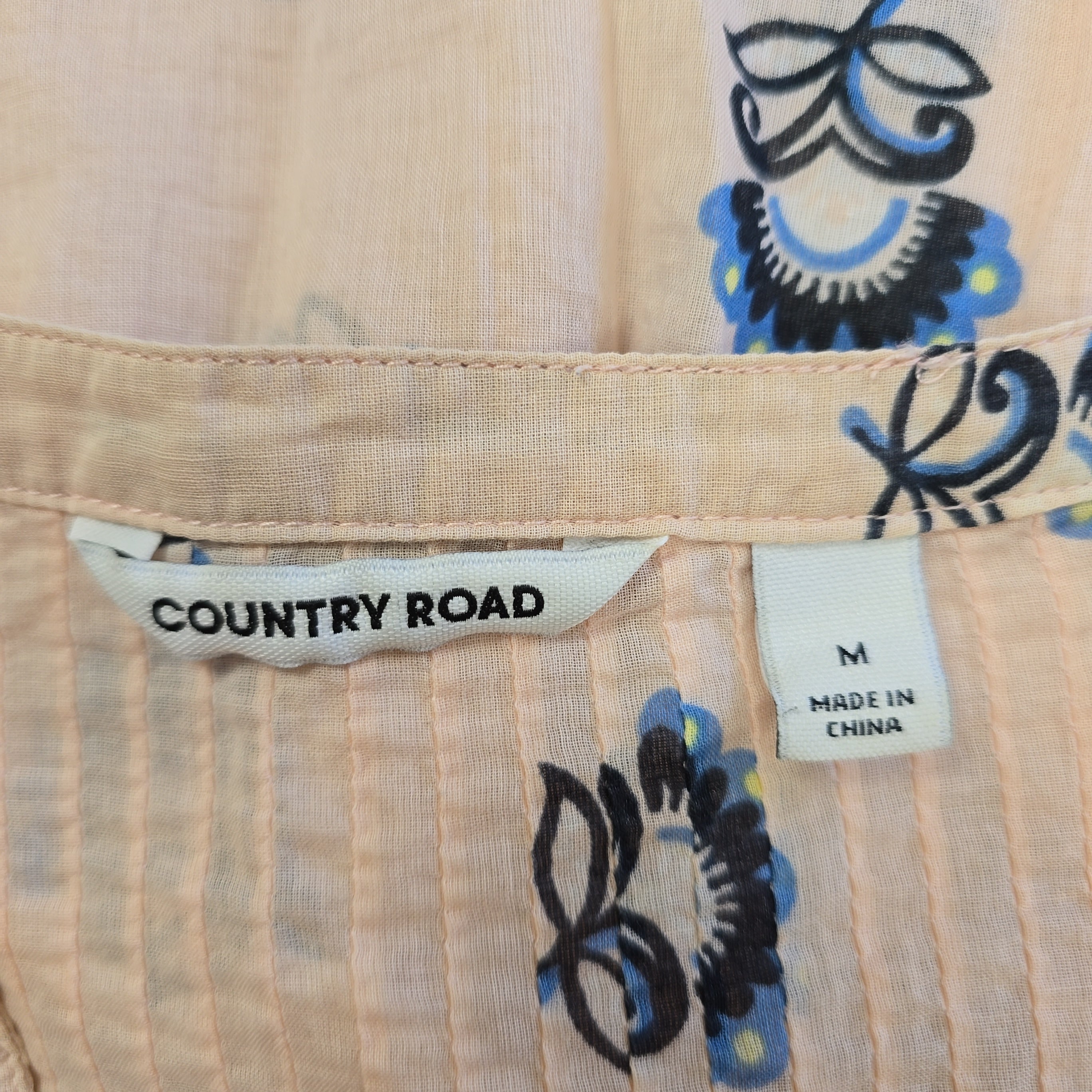 Close-up of a shirt with floral patterns and 'Country Road' label.