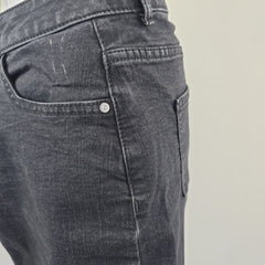 Close-up of a gray denim pocket with a button on a plain background