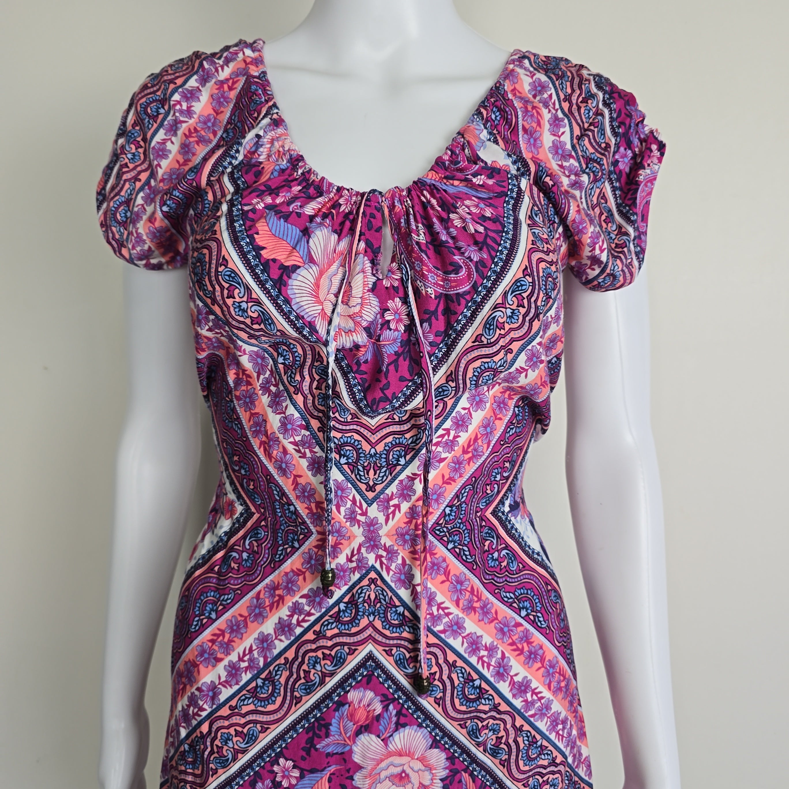 Mannequin wearing a vibrant, patterned dress with a pink and purple color scheme.