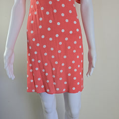 Red dress with white polka dots on a mannequin against a plain background
