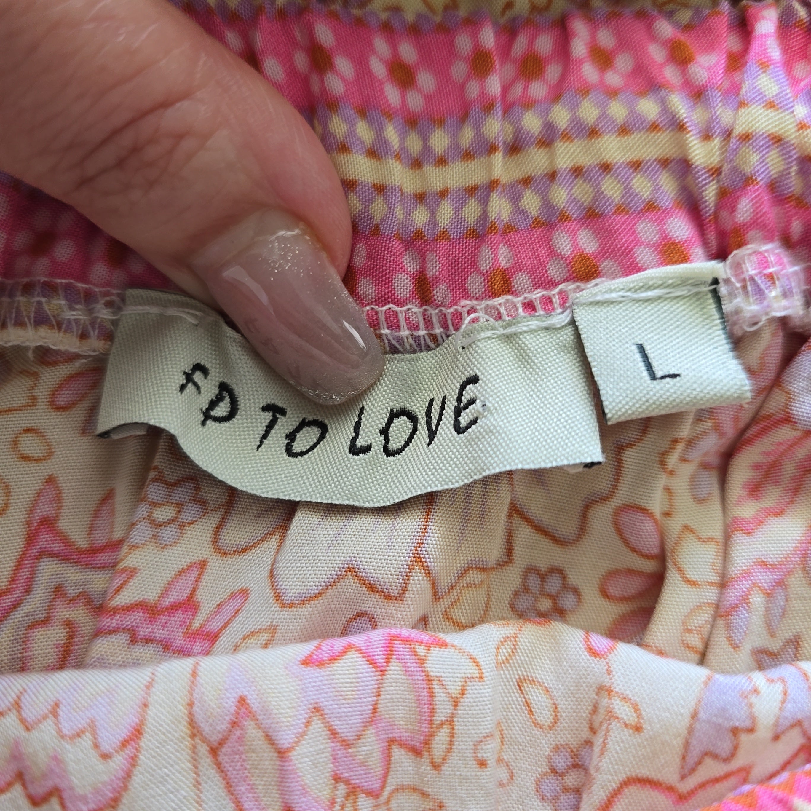 Fabric with a label reading 'FP TO LOVE' held by a hand against a colorful fabric background.