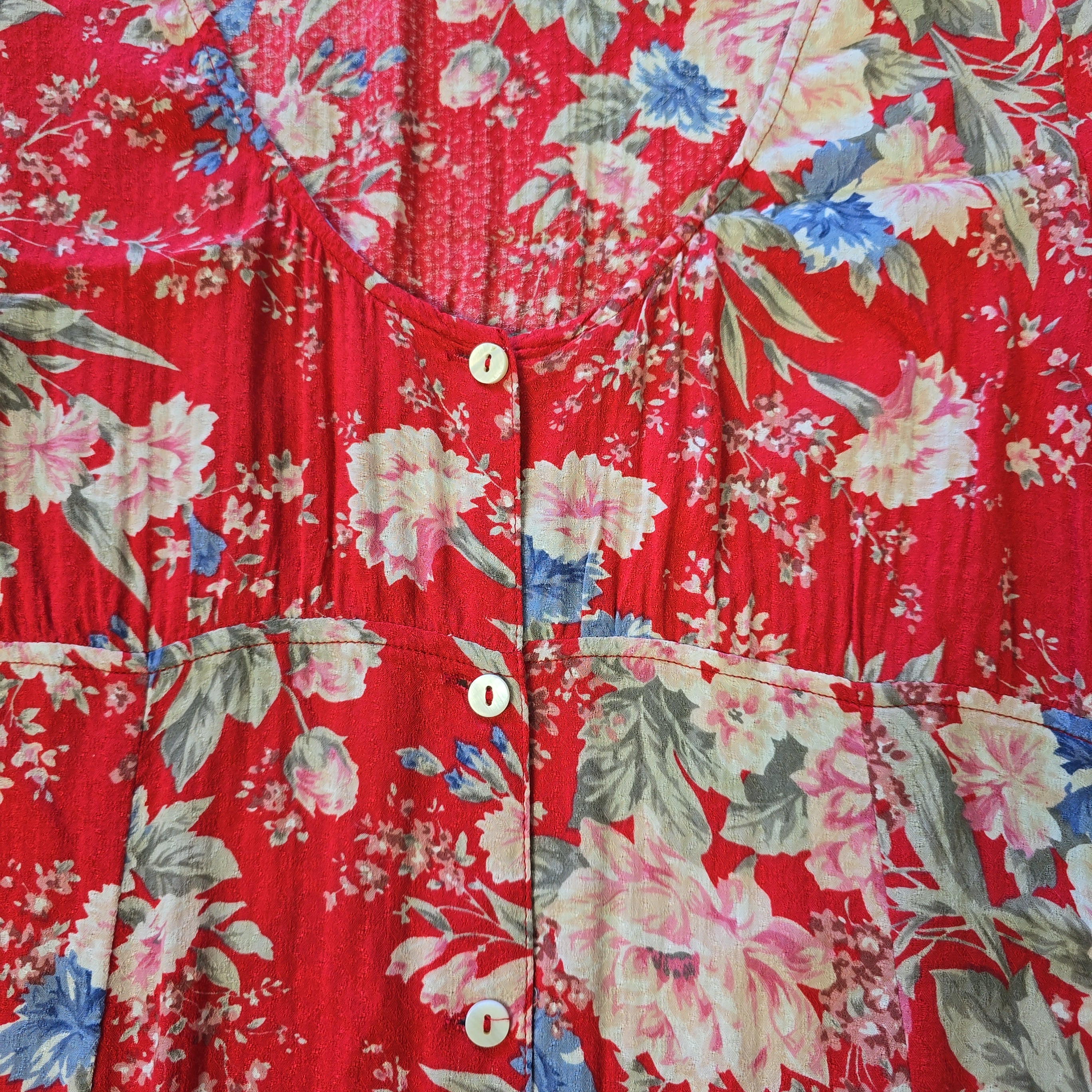 Red floral shirt with a pattern of pink and blue flowers on a red background