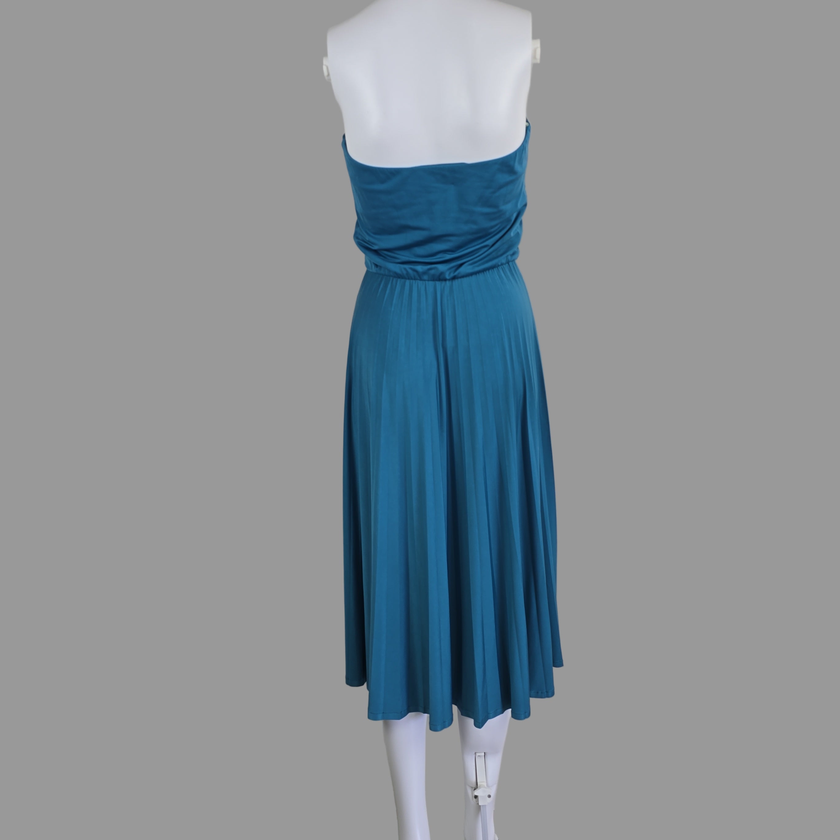Blue pleated dress on a mannequin against a white wall.
