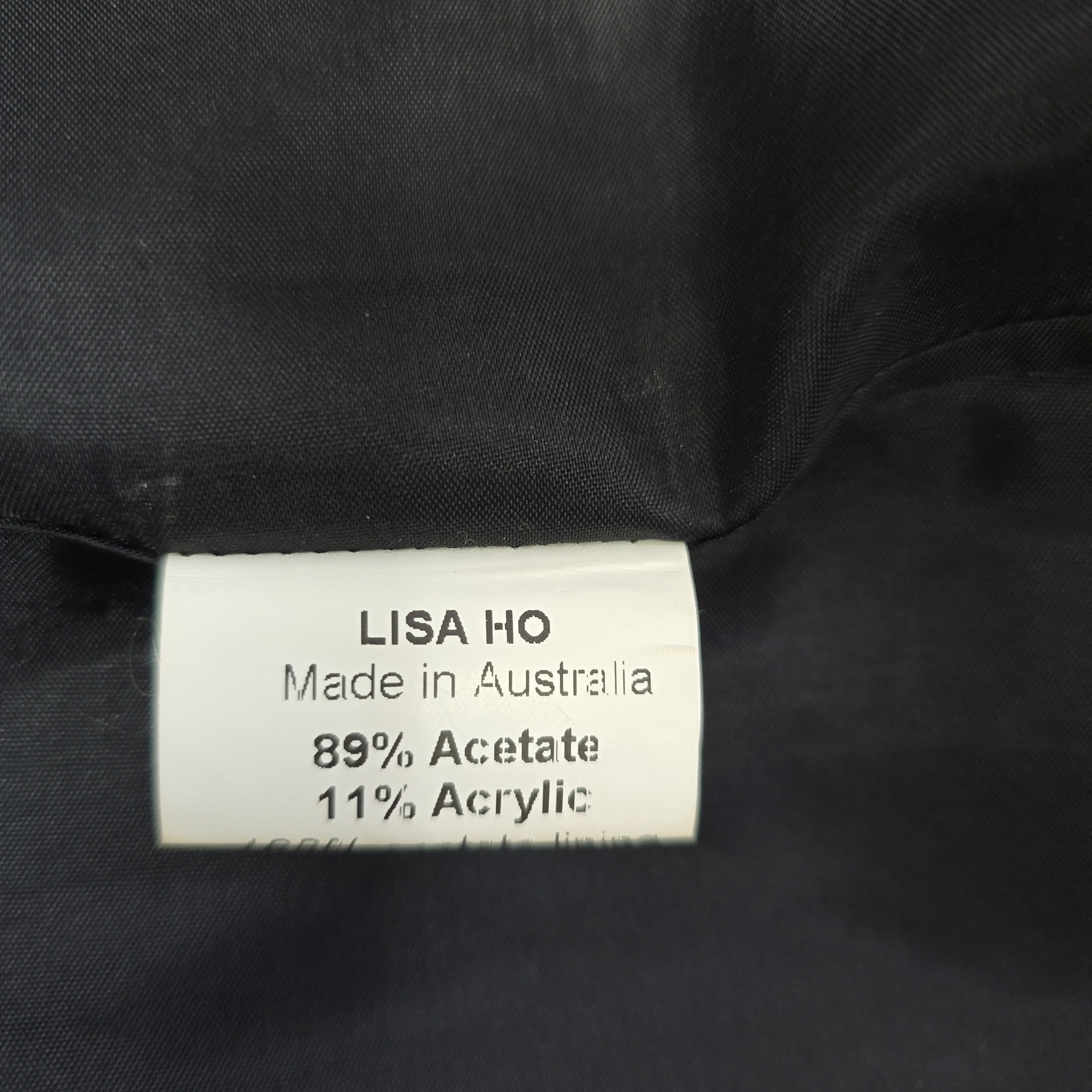 Close-up of a label on black fabric with 'Lisa Ho' branding.