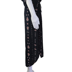 Black fabric with pink floral patterns on a white mannequin arm against a neutral background