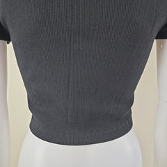 Close-up of a dark gray ribbed top sleeve on a mannequin against a beige background