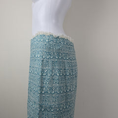 Teal textured skirt on a light gray surface with a neutral background