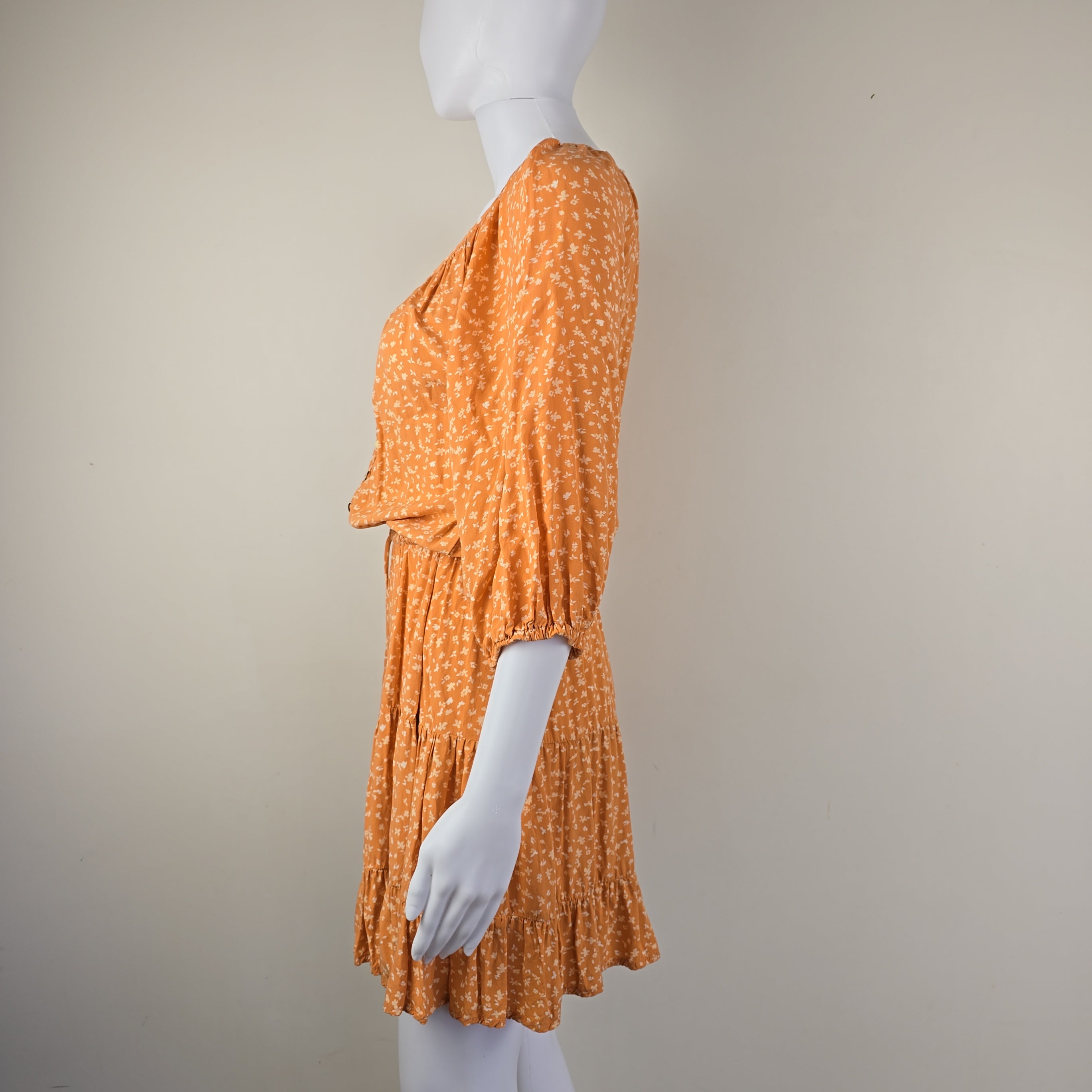 Orange textured dress on a mannequin with a plain background