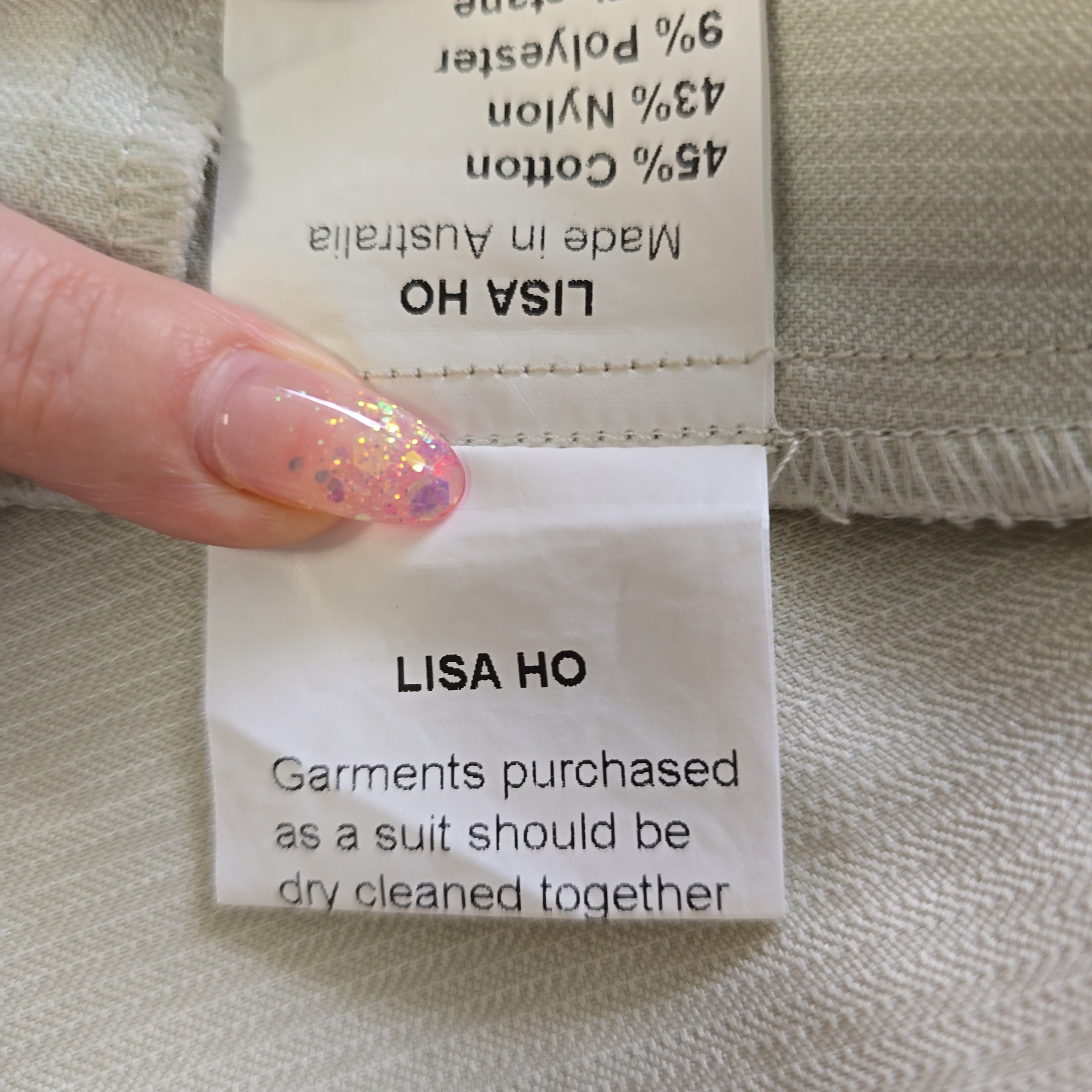 Close-up of a Lisa Ho clothing label on fabric with a hand holding it.