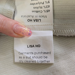Close-up of a Lisa Ho clothing label on fabric with a hand holding it.