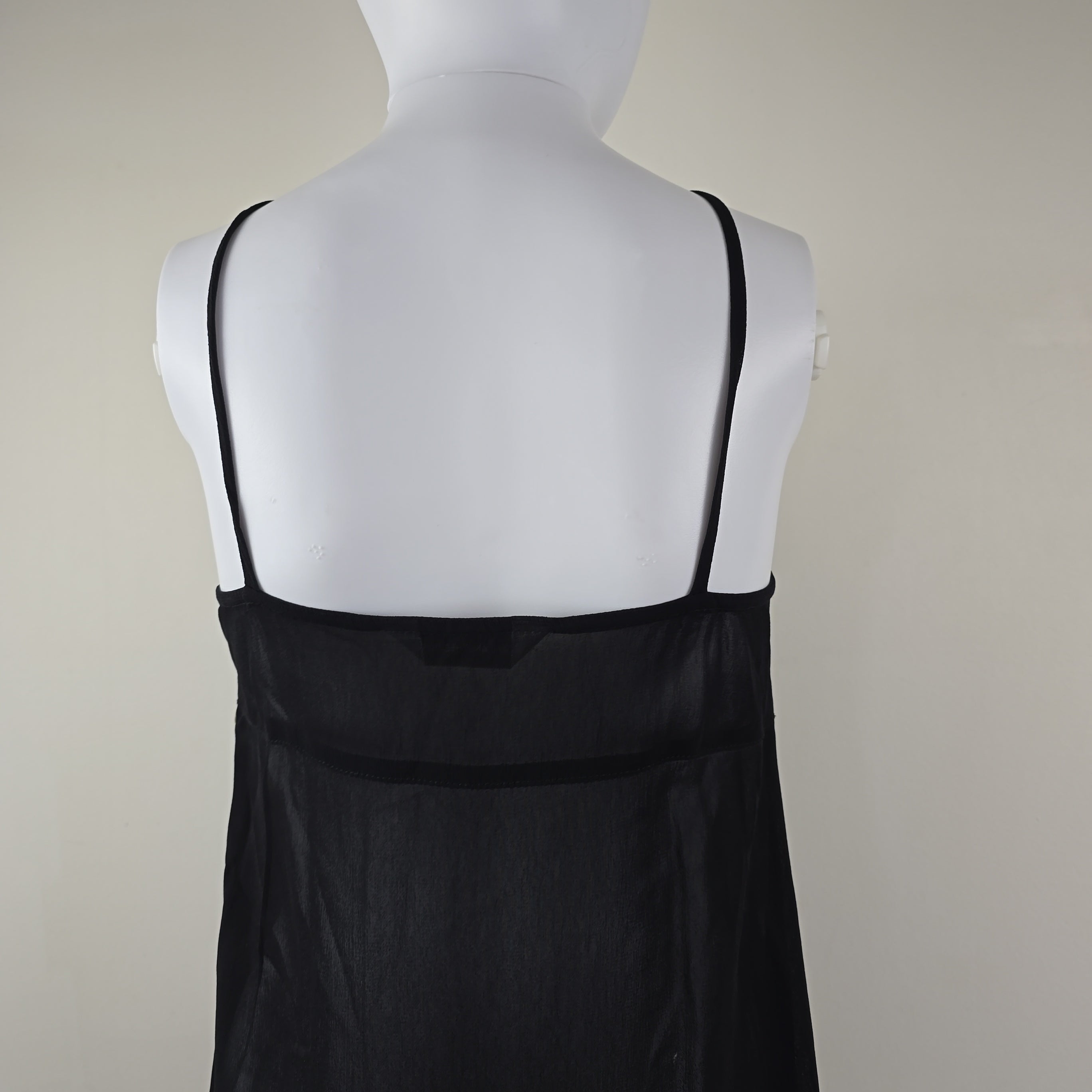 Mannequin wearing a black dress with a white top on a plain background
