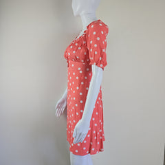 Red dress with white polka dots on a mannequin against a plain background