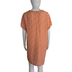 Orange patterned fabric on a mannequin against a beige background