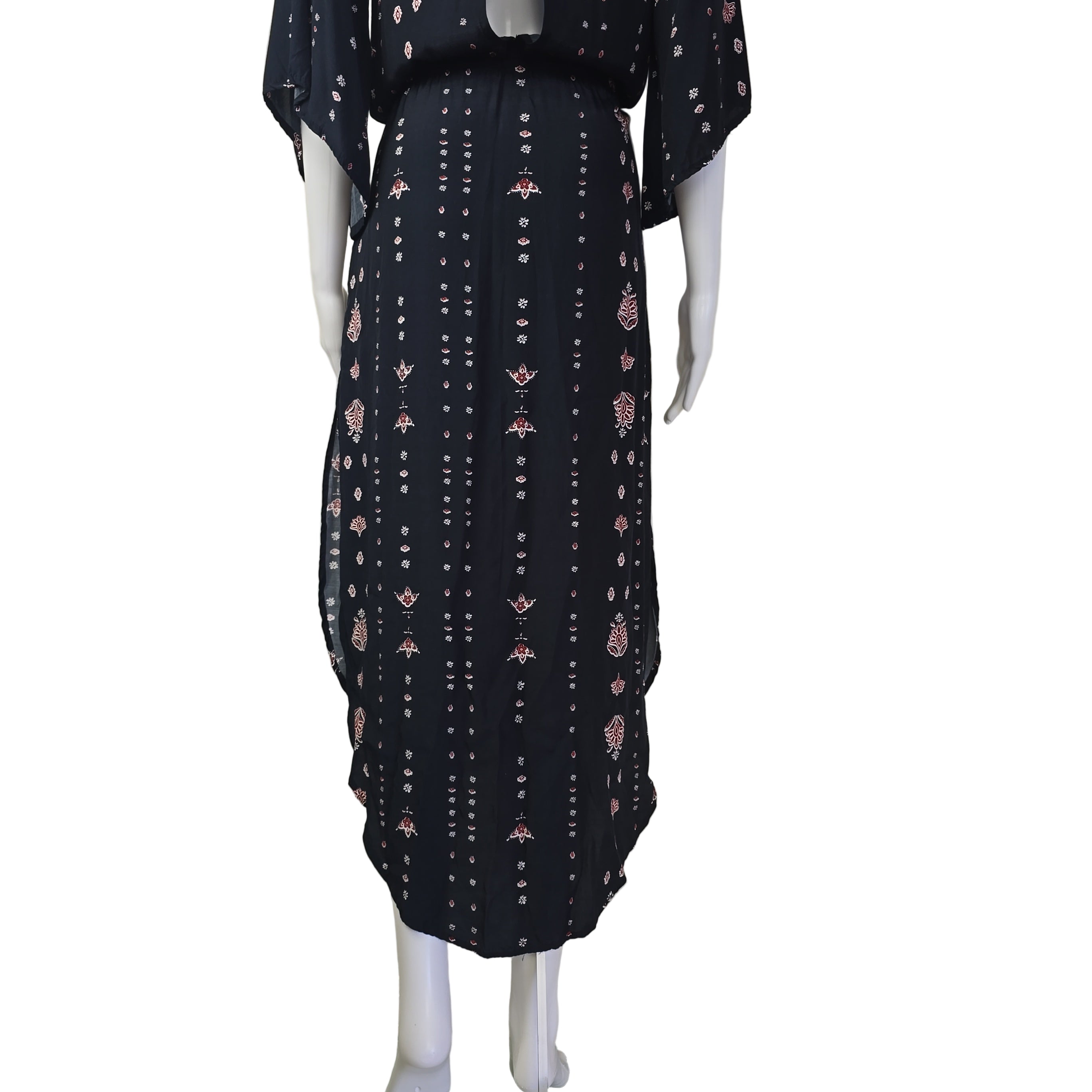 Black dress with pink floral pattern against a beige wall.