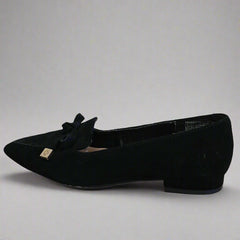 Black velvet flat shoe with a bow on a white surface