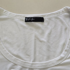 Close-up of a white tank top with a black label on a beige background