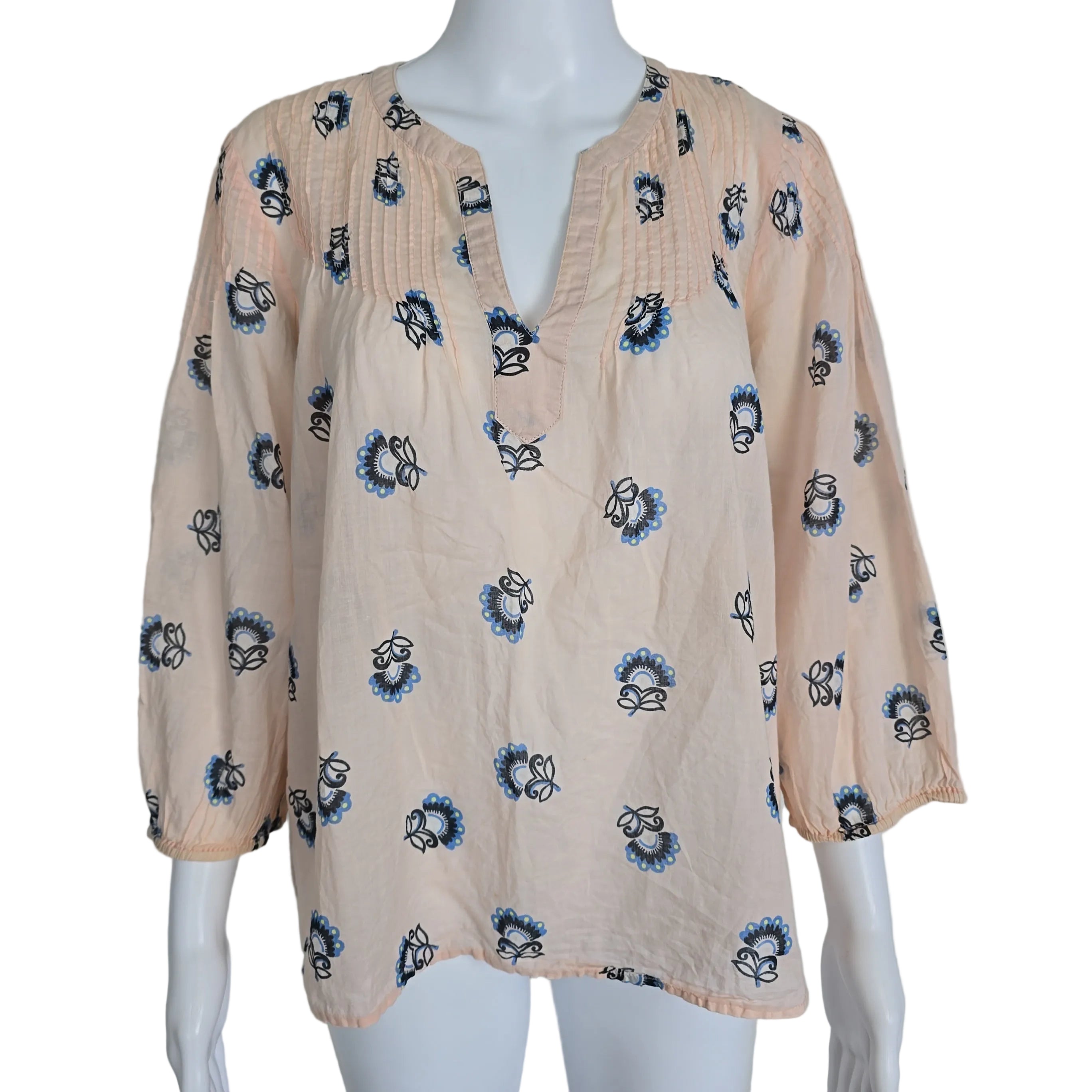 Mannequin wearing a beige top with blue floral patterns on a plain background