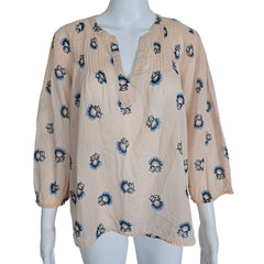 Mannequin wearing a beige top with blue floral patterns on a plain background