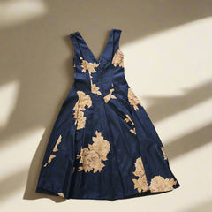 Navy blue dress with gold floral embroidery on a tiled floor.
