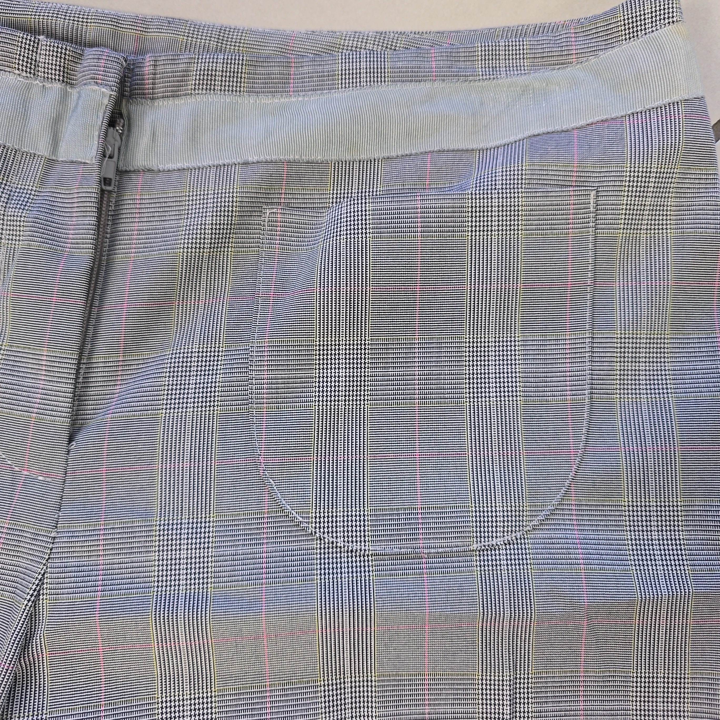 Gray plaid fabric with a pocket and zipper detail on a light gray background
