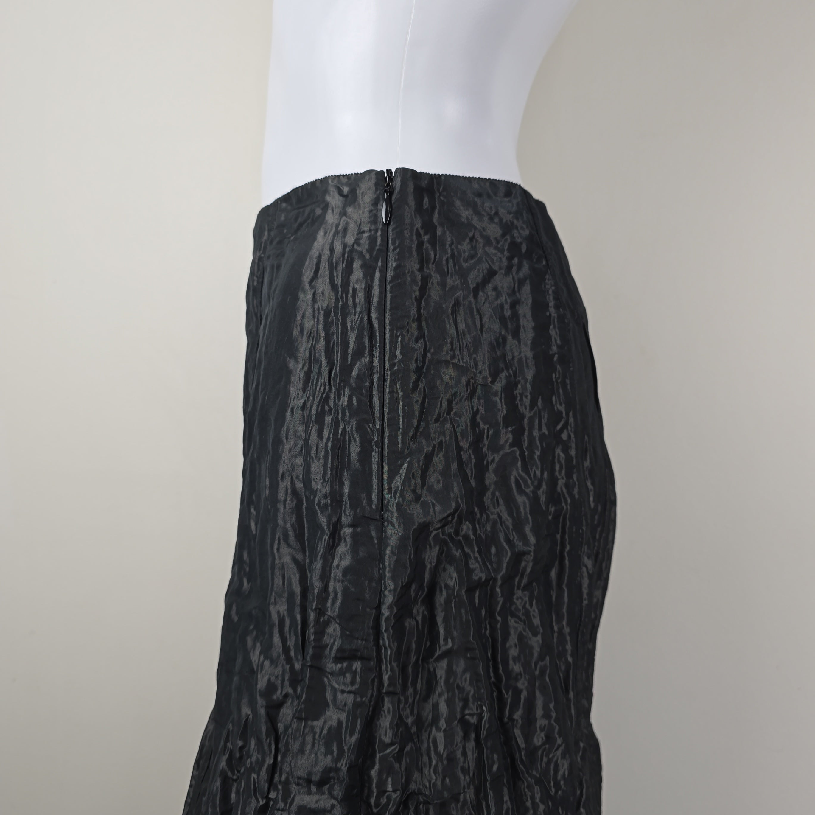 Black textured skirt on a mannequin arm against a neutral background