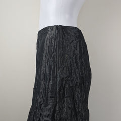 Black textured skirt on a mannequin arm against a neutral background