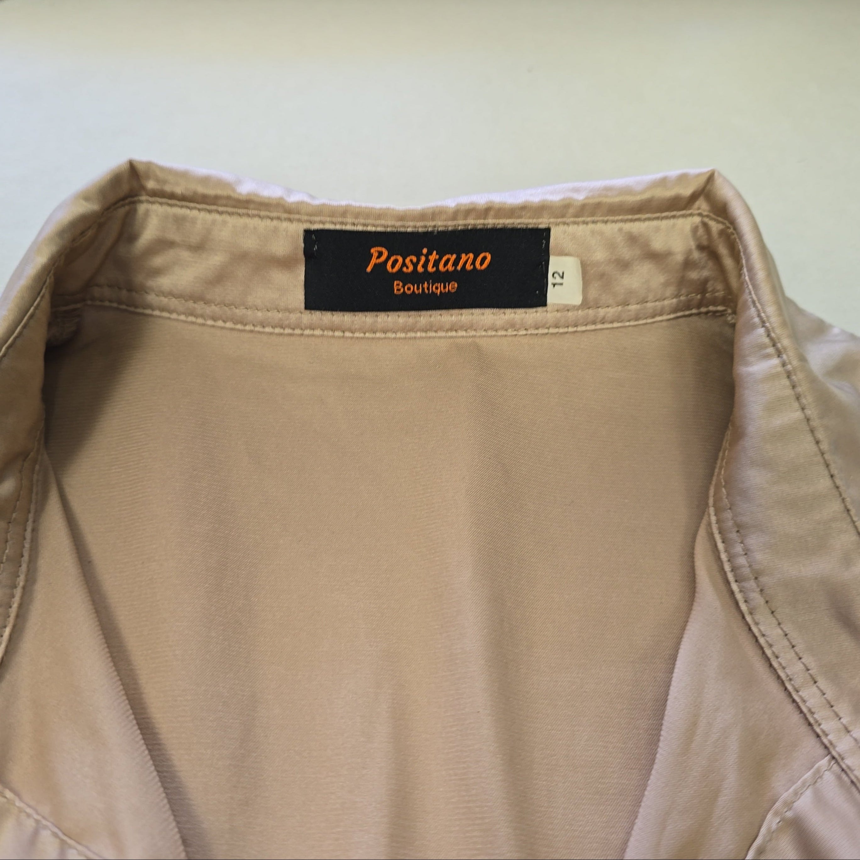 Beige top with a 'Positano Boutique' label on a white background