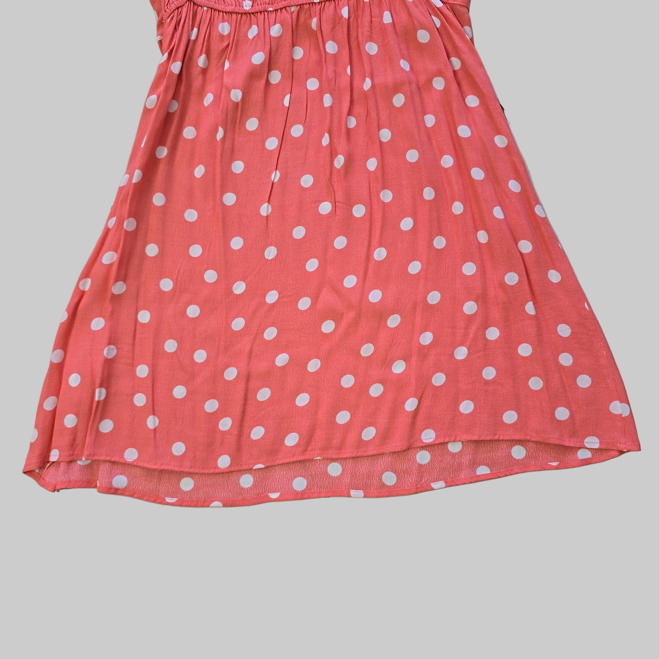 Pink dress with white polka dots on a tiled floor