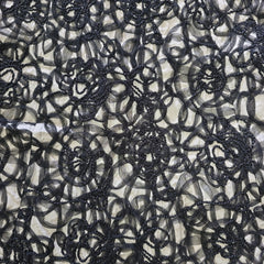 Close-up of black lace fabric with intricate patterns on a neutral background