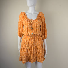 Orange textured dress on a mannequin against a beige background