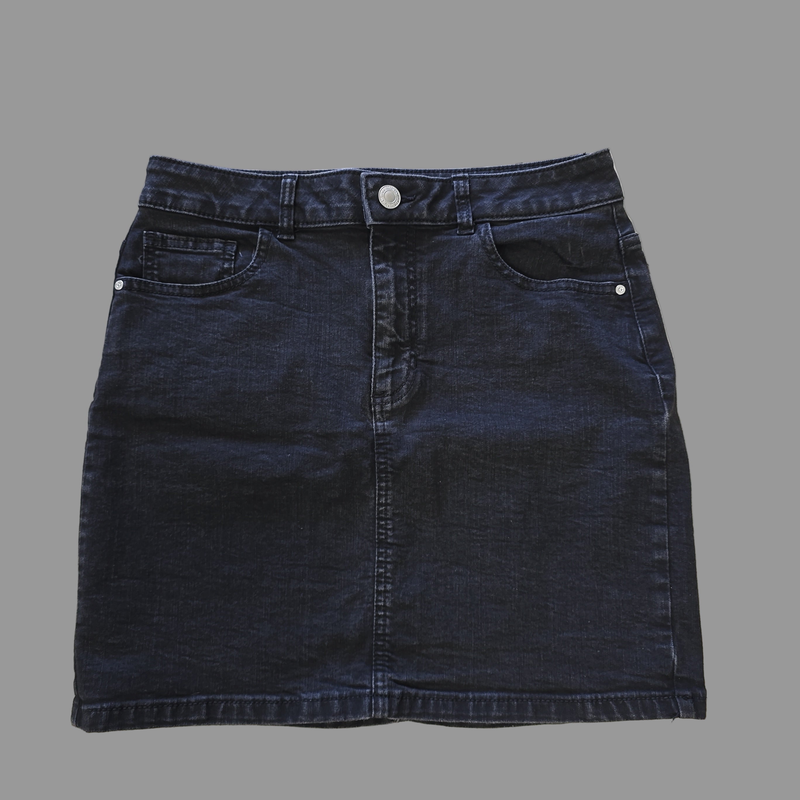 Folded dark grey denim skirt on a tiled floor