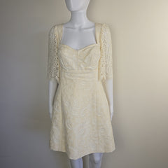Mannequin wearing a cream-colored lace dress on a plain background