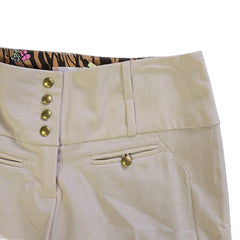 Close-up of beige pants with gold buttons on a neutral background