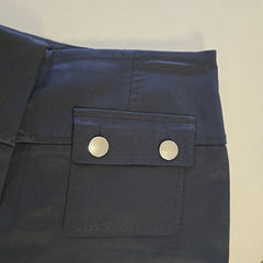 Close-up of black pants with two silver buttons on a beige background