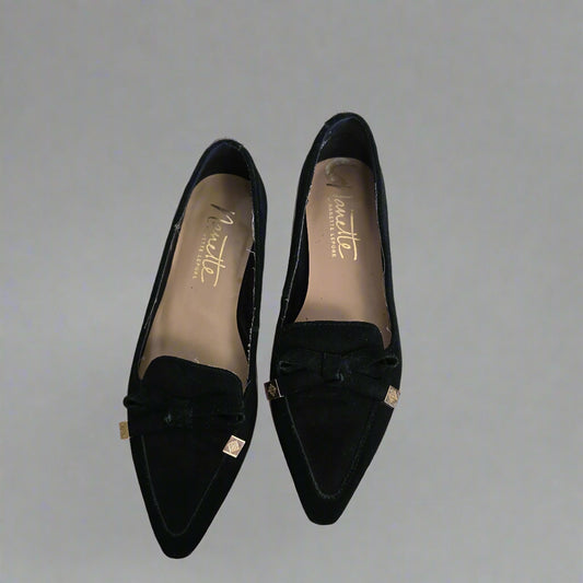 Pair of black loafers with 'Manette' branding on a tiled floor. 1024
