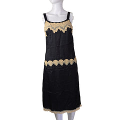 Black dress with gold lace trim on a mannequin against a beige background