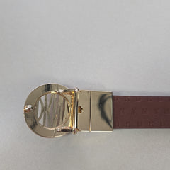 Gold belt buckle with a brown leather strap on a gray background