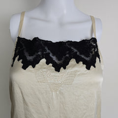 White lace garment on a mannequin with black lace trim against a plain background