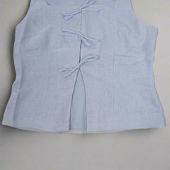 Light blue sleeveless top with bow details on a tiled floor