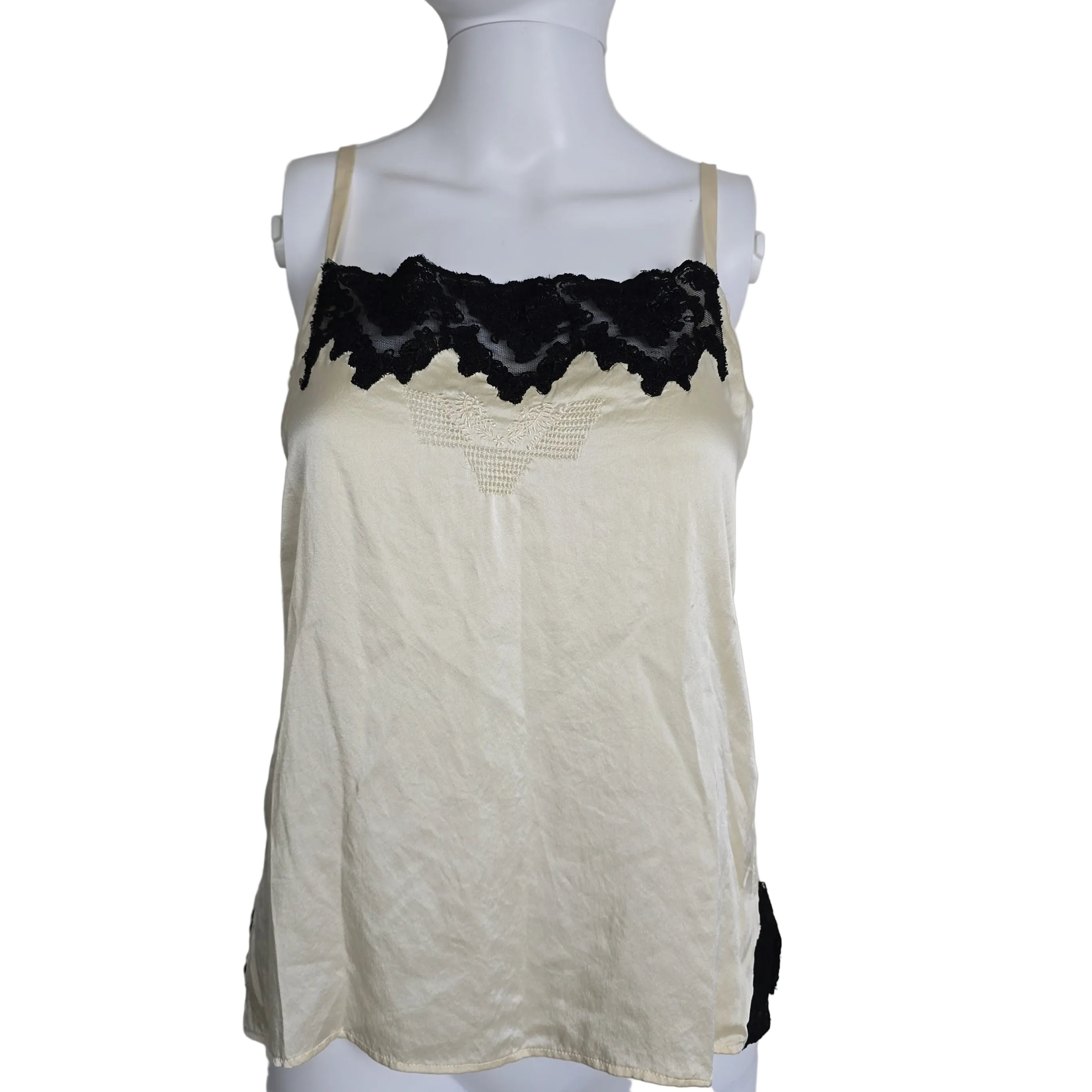 Mannequin wearing a white top with black lace details on a plain background