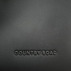 Text 'COUNTRY ROAD' embossed on a dark fabric surface