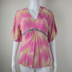 Mannequin wearing a pink and beige top with silver lace on a plain background