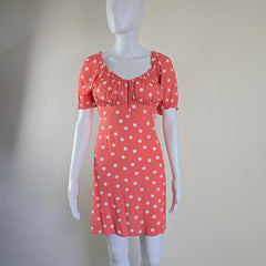 Mannequin wearing a coral dress with white polka dots on a plain background