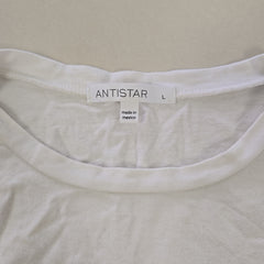 Close-up of a white garment with an 'ANTISTAR' label on a beige background